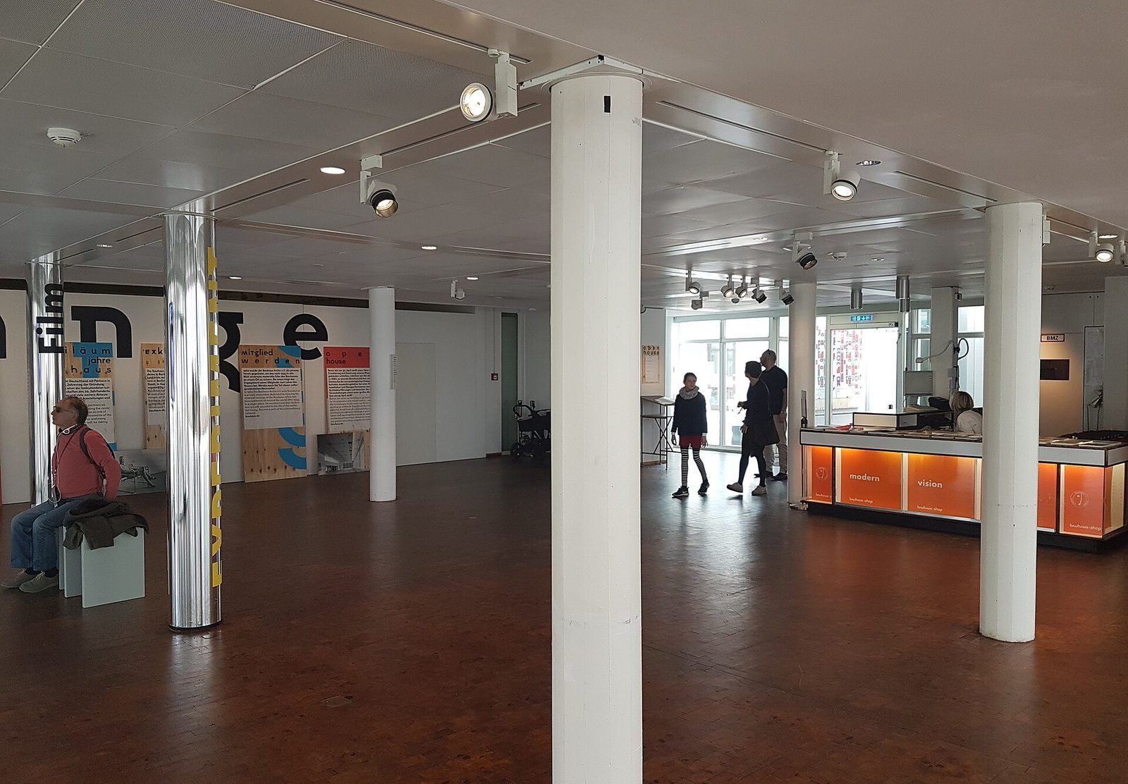 Foajeen i Bauhaus-Archiv med hvite og forkrommede søyler, typografi på veggene og museumsbutikken