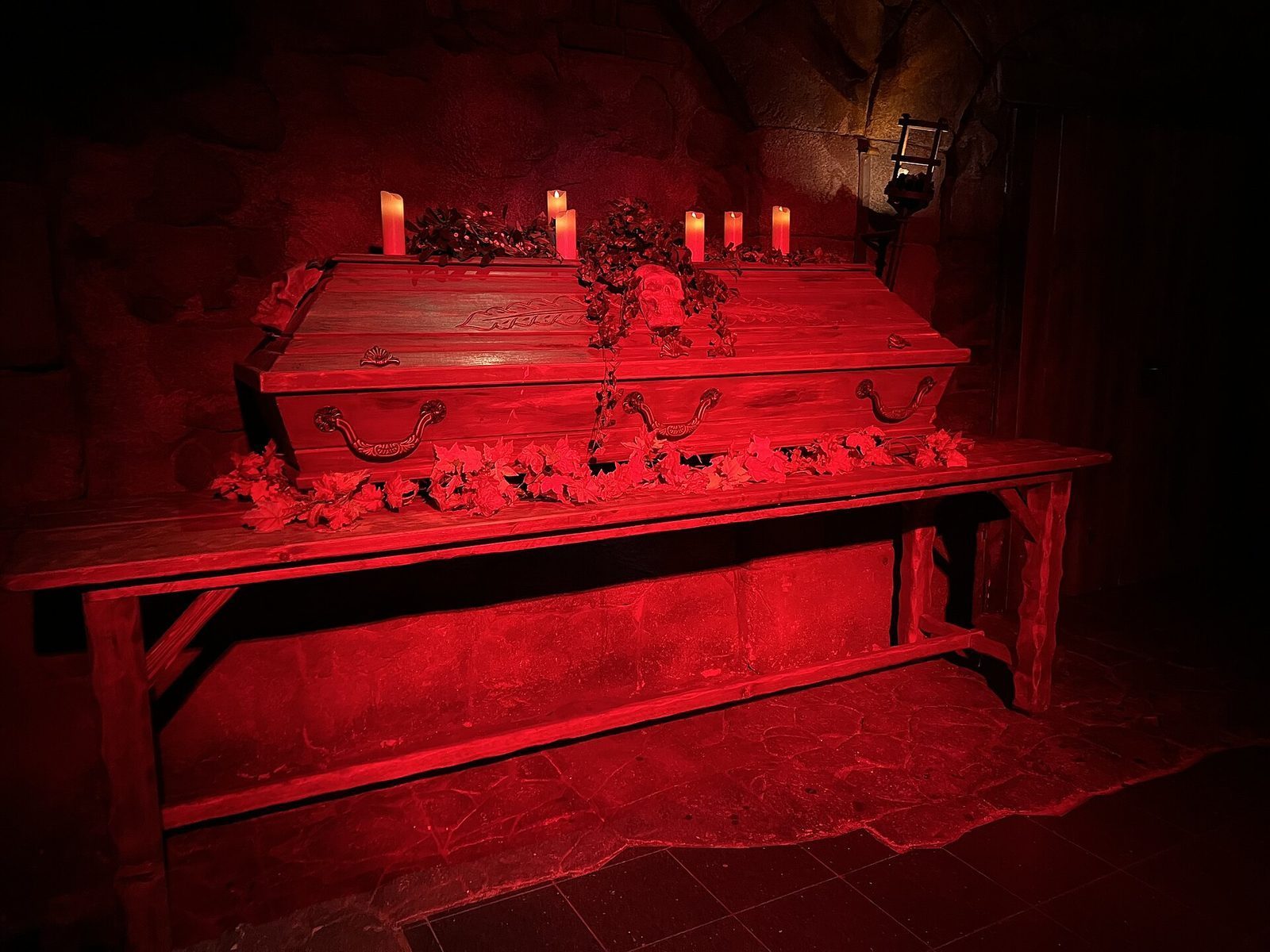 Kulisse fra Berlin Dungeon med en kiste, en hodeskalle og stearinlys i uhyggelig rødt lys