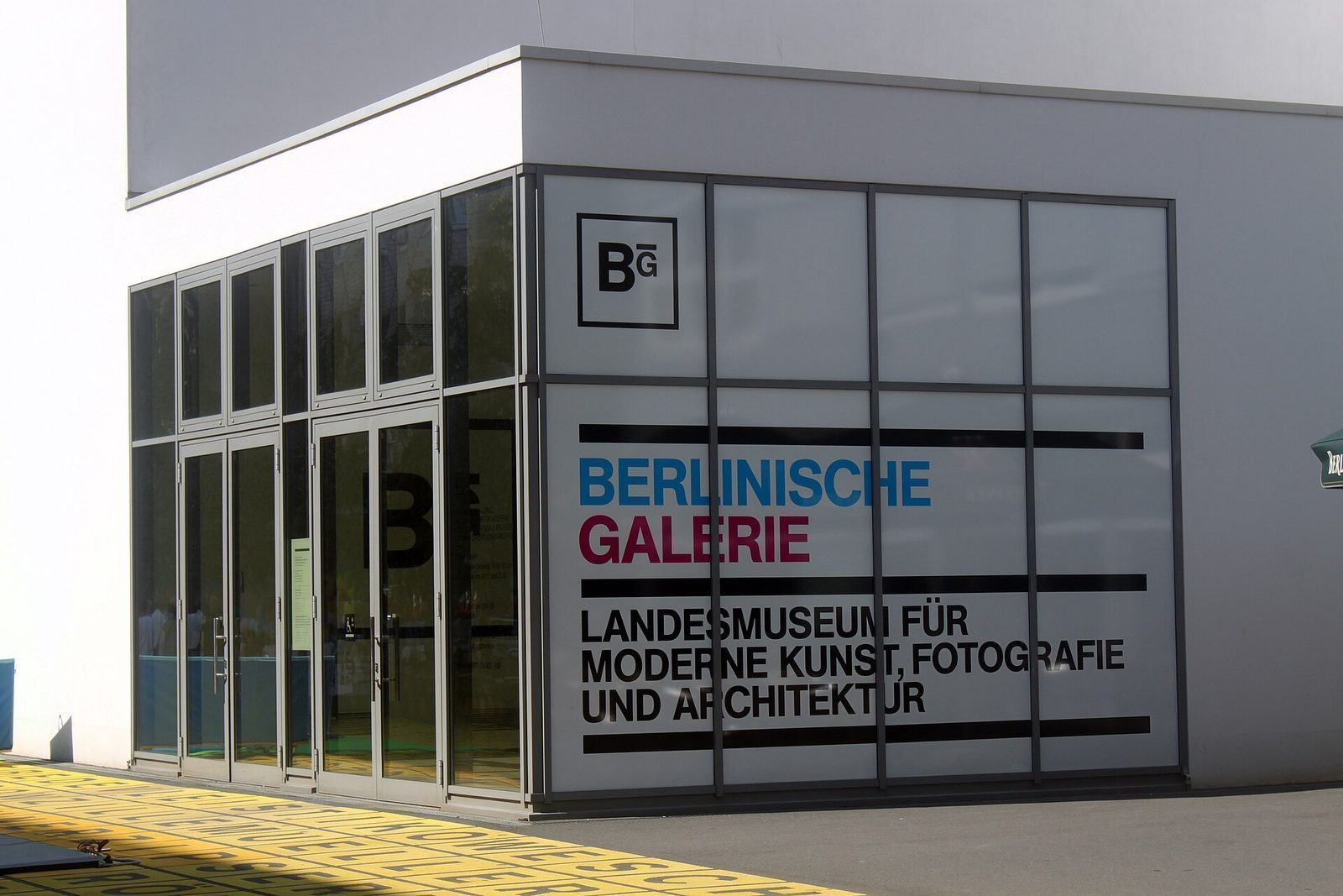 Inngangen til Berlinische Galerie med glassdører og navnetrekket «Landesmuseum für moderne Kunst, Fotografie und Architektur»