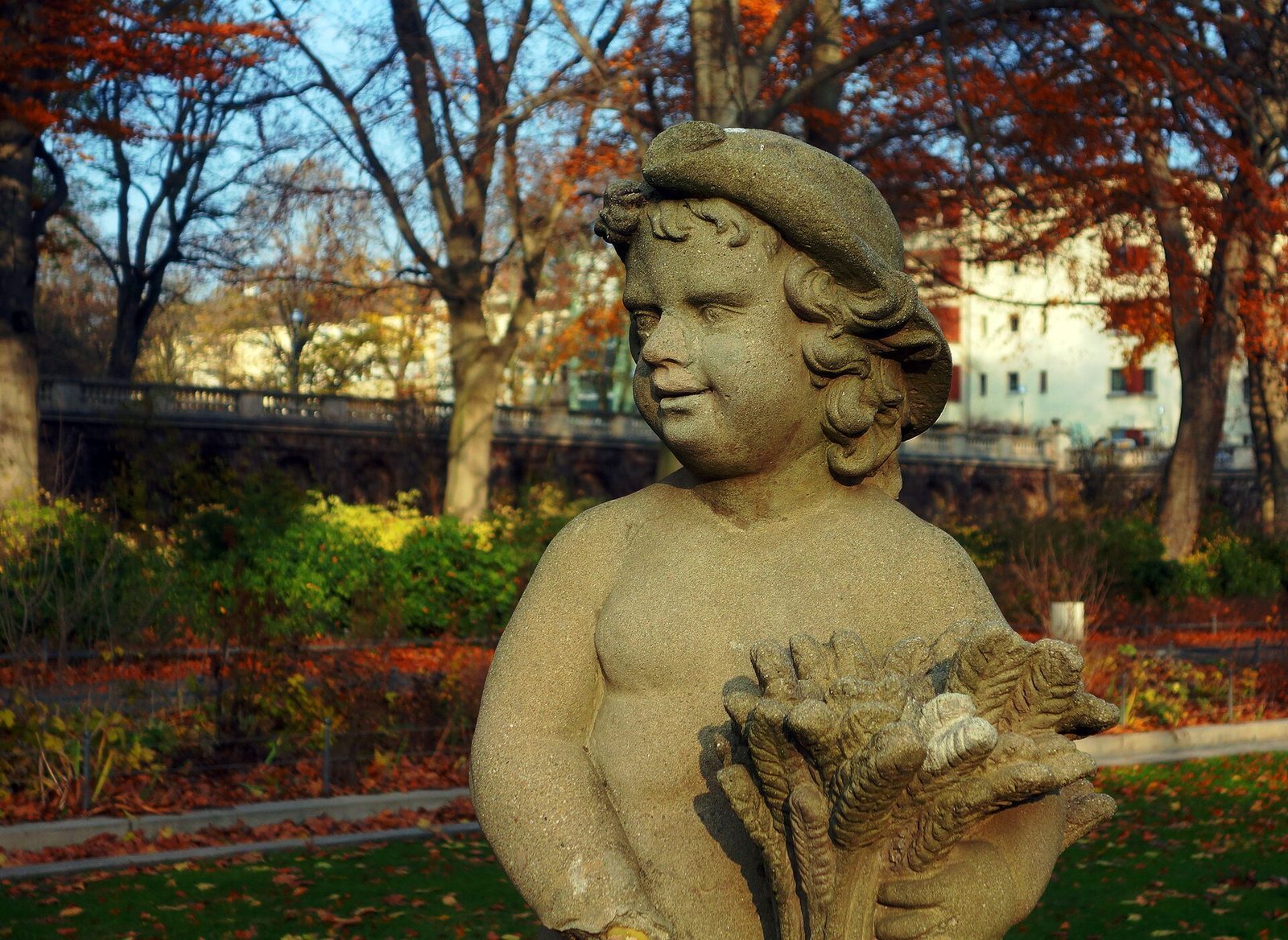 Sandsteinsfigur av en gutt med kornnek i Koernerpark, omgitt av rodt hostlov
