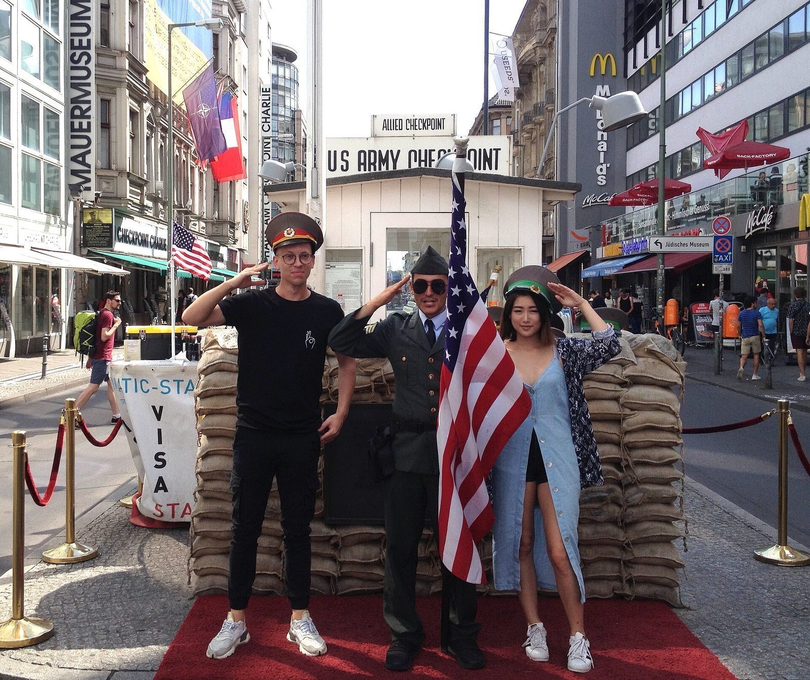 Turister som poserer for foto med utkledde «vakter» i vaktbua ved Checkpoint Charlie