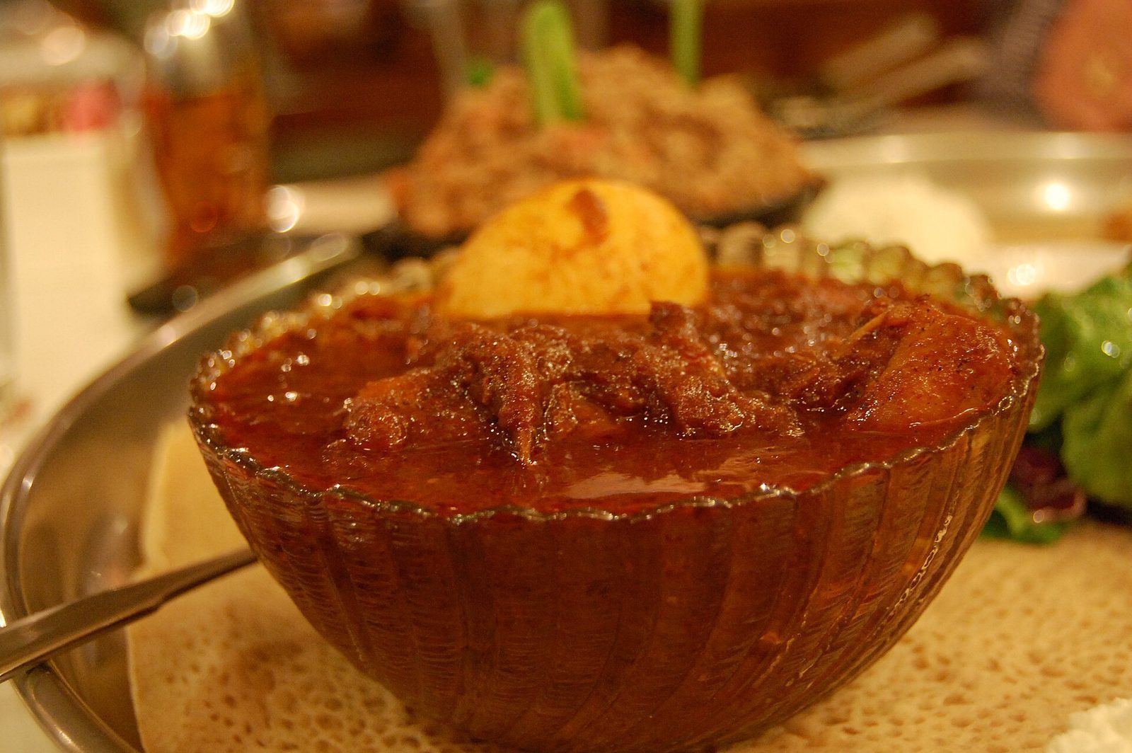 Nærbilde av doro wat, en krydret etiopisk kyllinggryte med et kokt egg, servert på injera