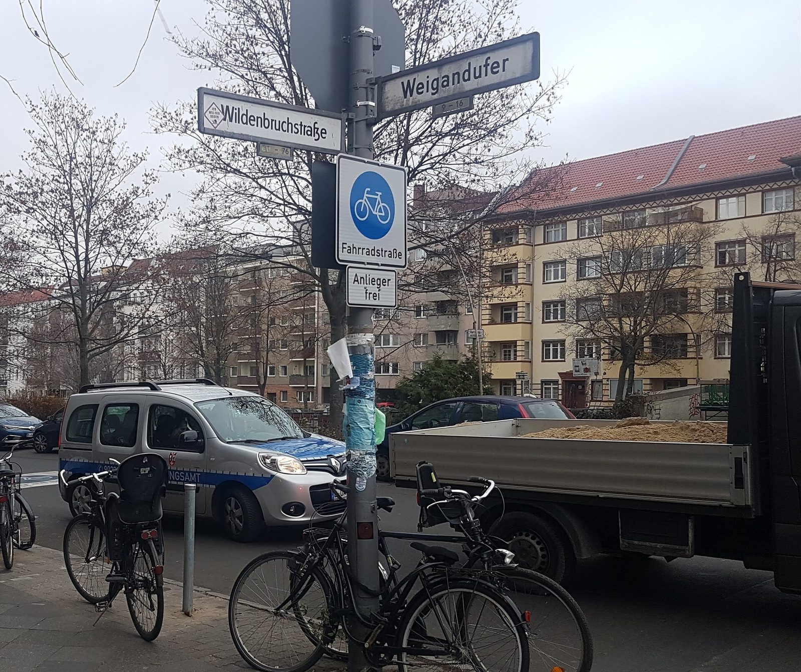 Skiltet «Fahrradstraße» med sykkelsymbol og parkerte sykler ved et gatehjørne på Weigandufer i Neukölln