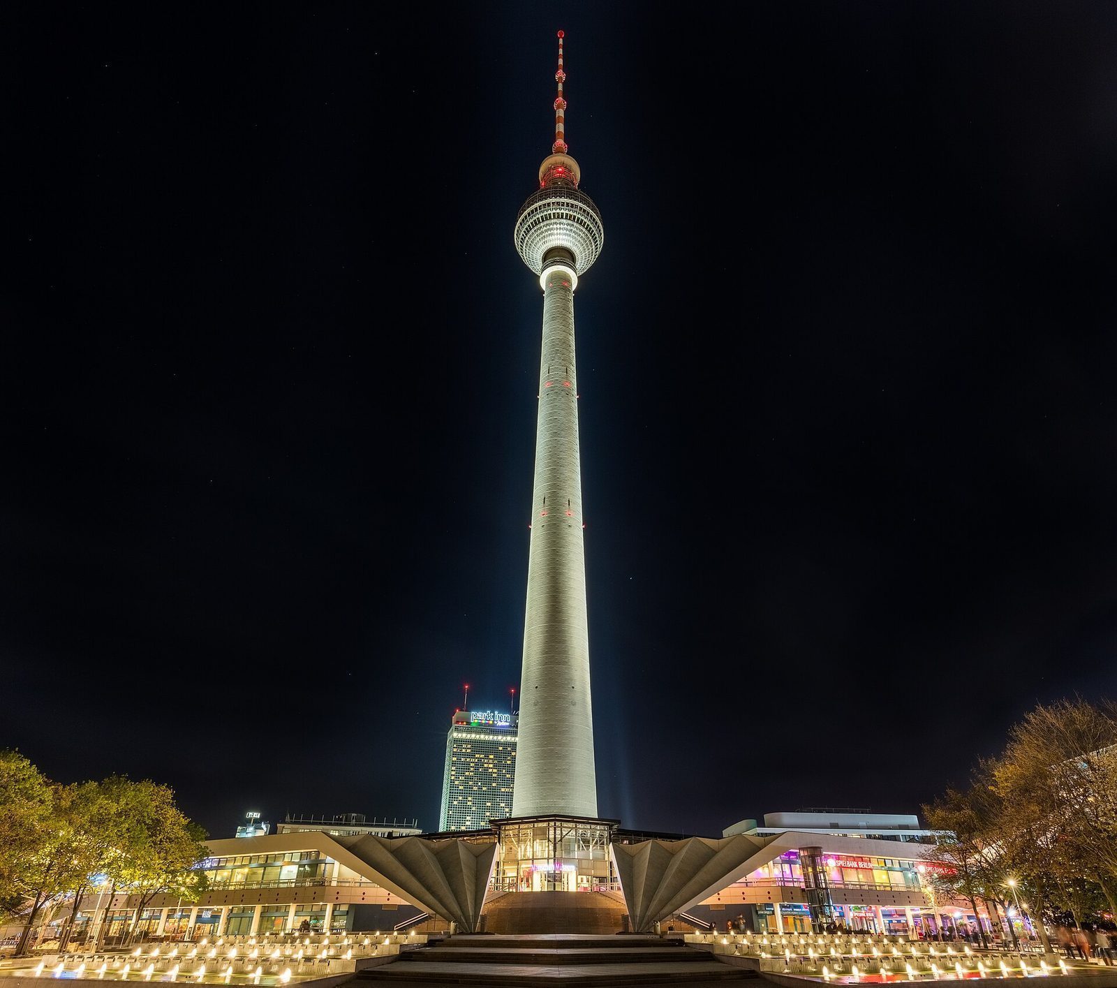 Fernsehturm opplyst om kvelden over fontenene på Alexanderplatz