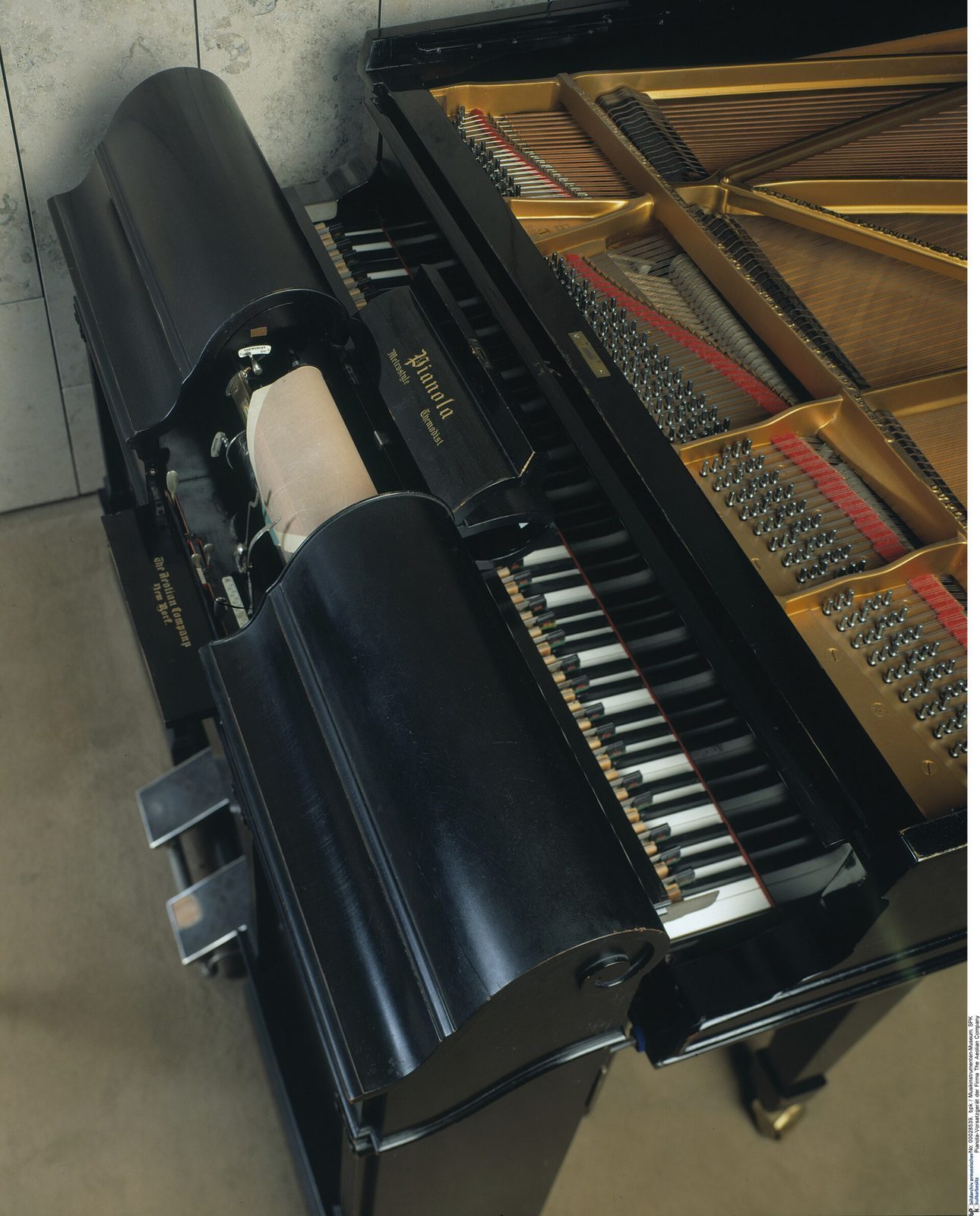 Et gammelt selvspillende Pianola-instrument med papirrull og mekanikk foran de forgylte strengene i et flygel
