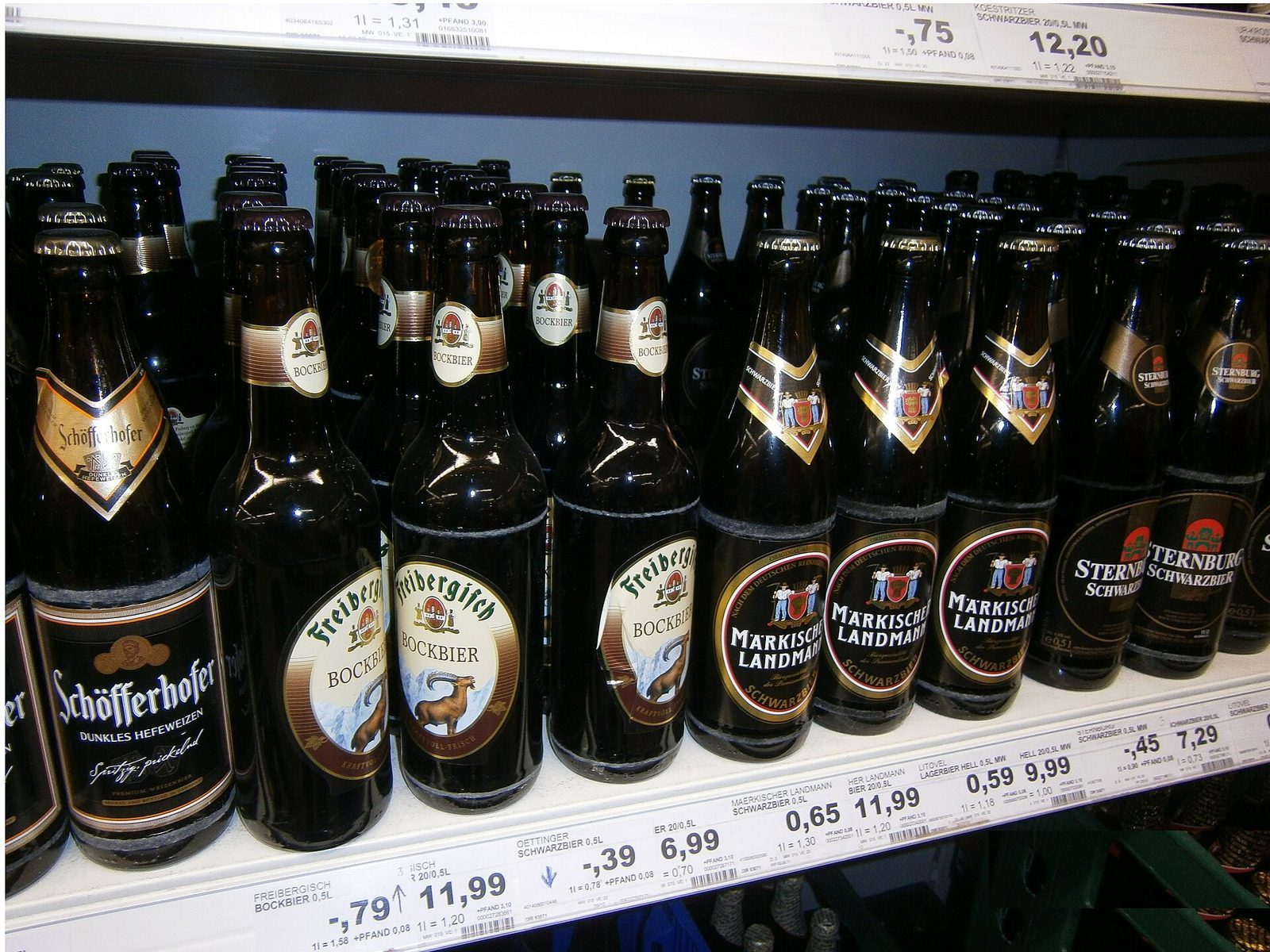 Butikkhylle full av tyske ølflasker som Schwarzbier og Bockbier med prislapper