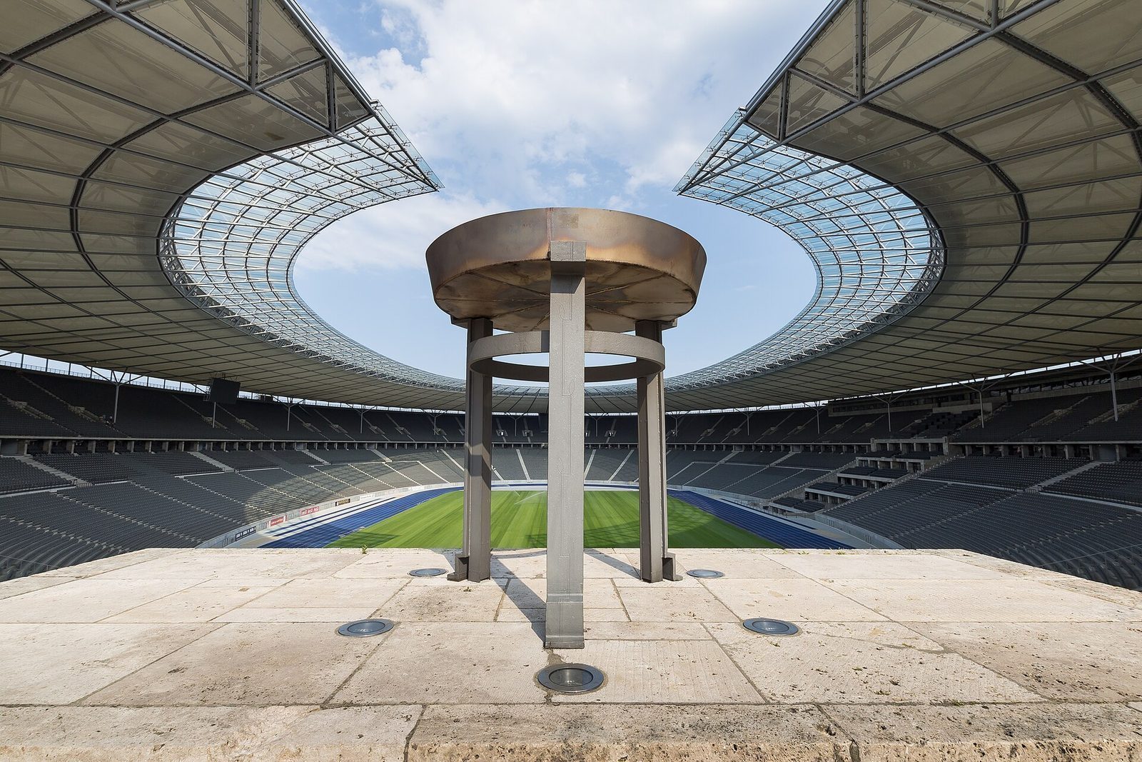 Innsiden av Olympiastadion med tribunene, den blå løpebanen og den olympiske ilden