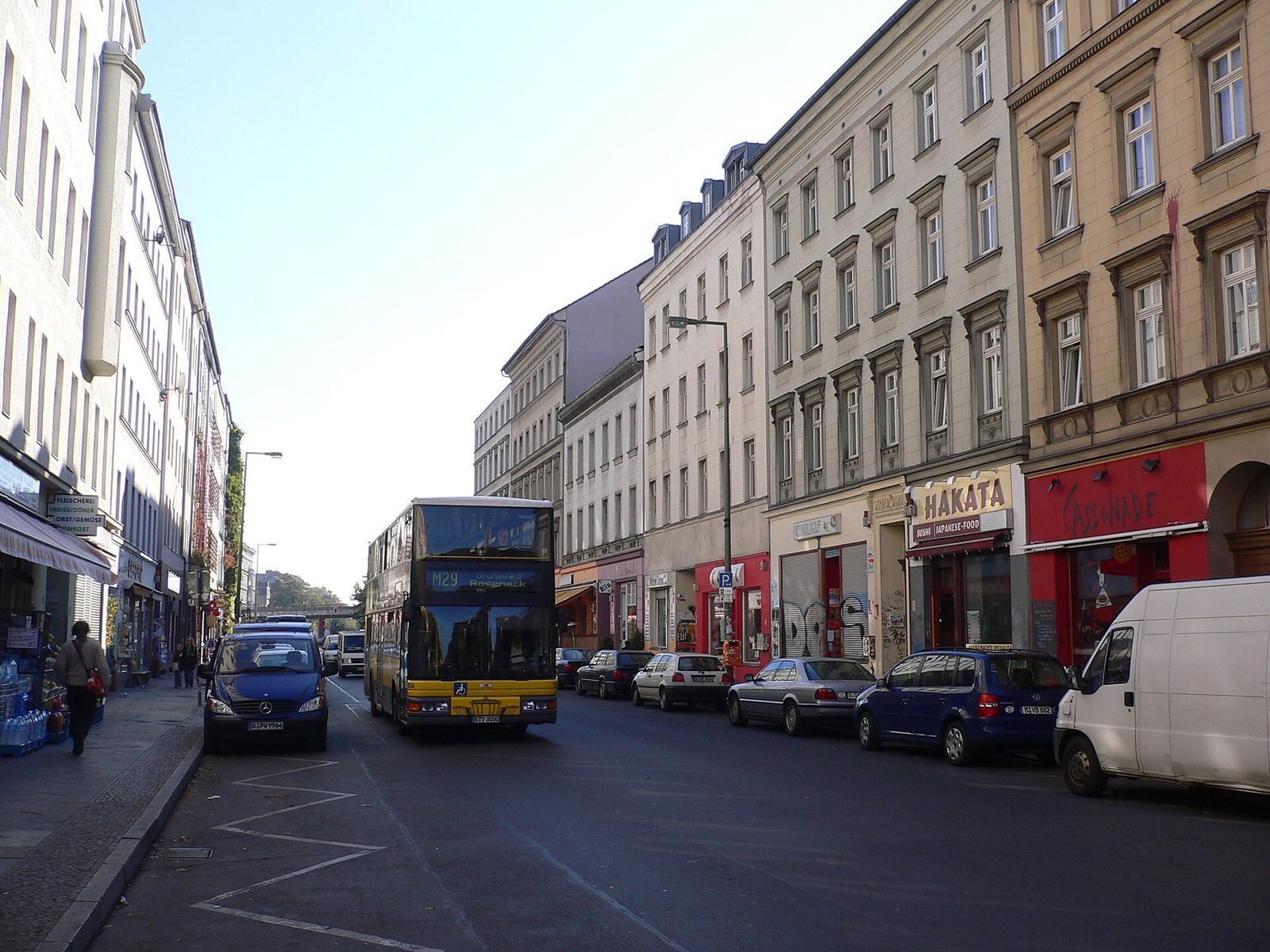 Oranienstraße i Kreuzberg med gul dobbeltdekkerbuss og butikker i gateplan