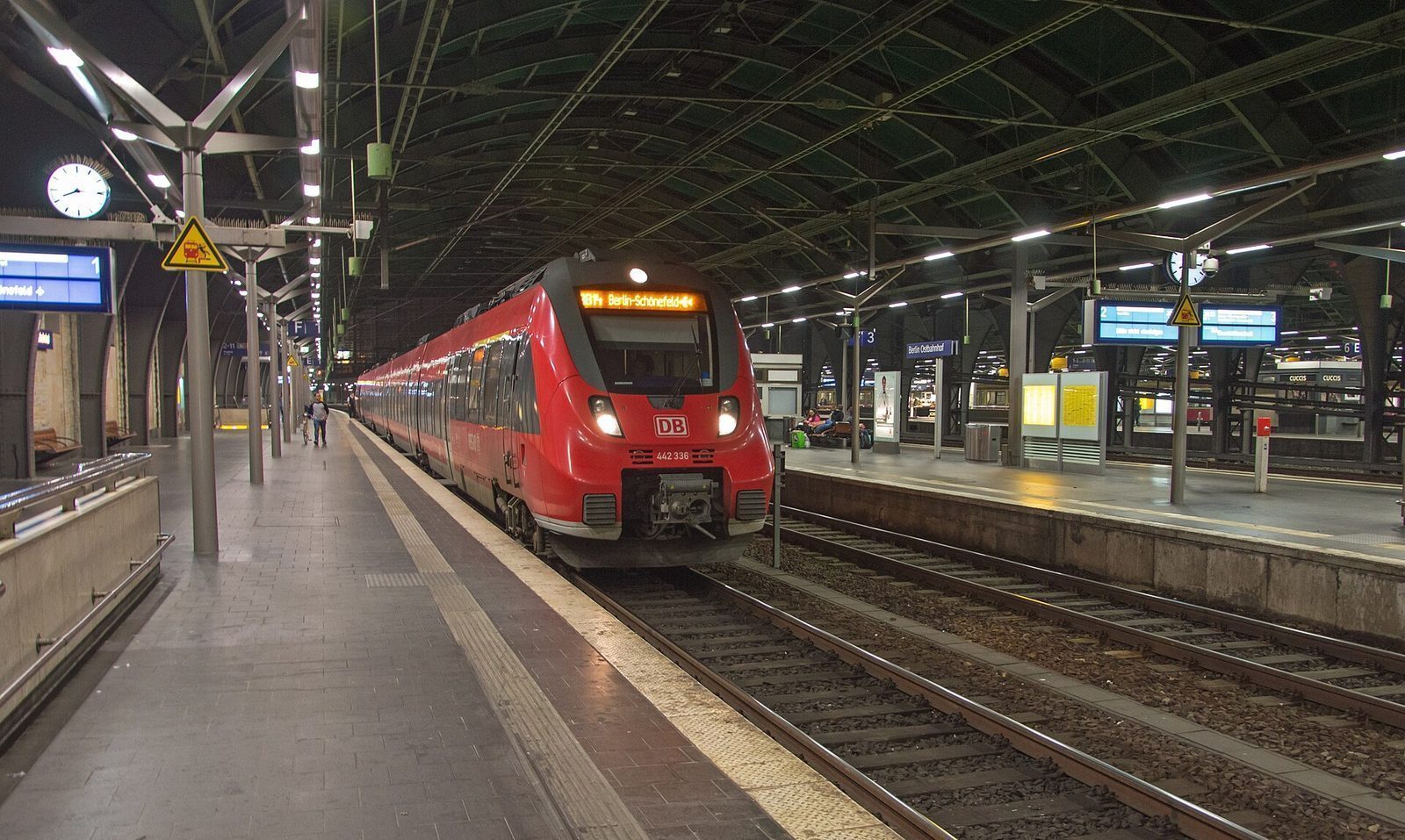 Rødt regionaltog ved perrongen på Berlin Ostbahnhof under buehallen om kvelden