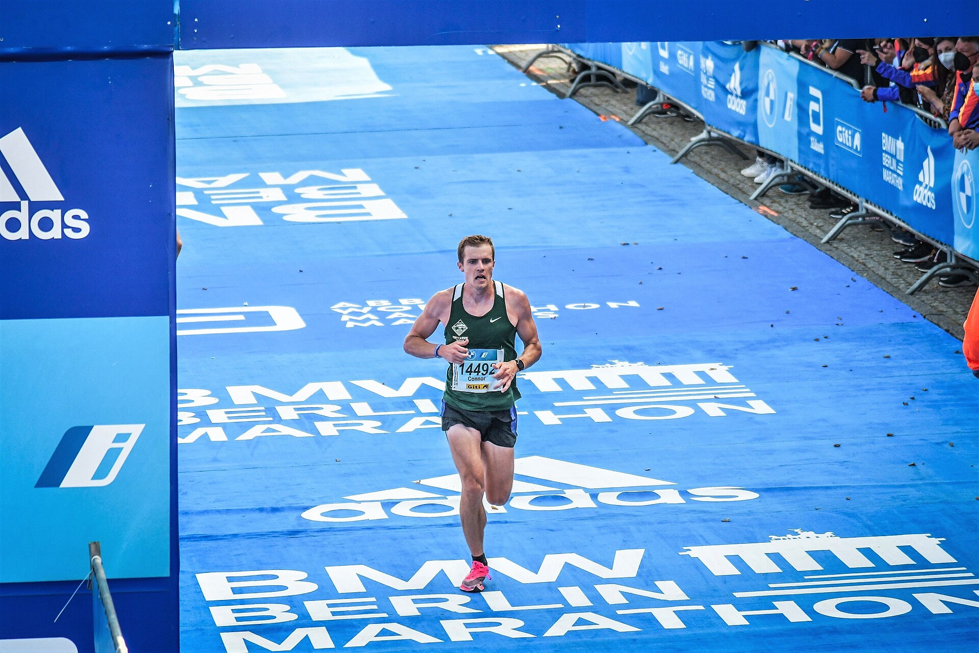 Løper på oppløpssiden under Berlin Marathon, med reklamevegger langs banen