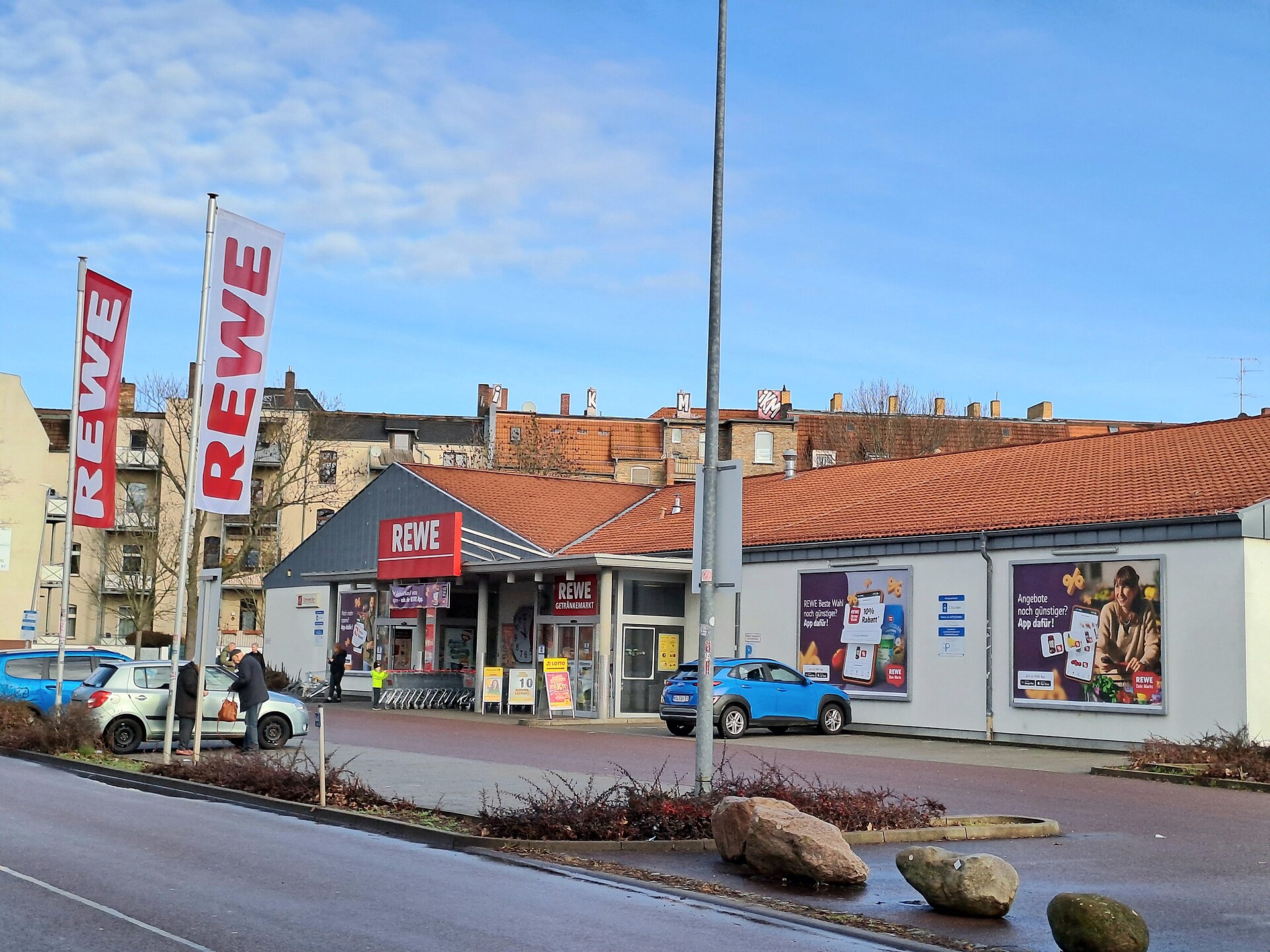 REWE-butikk i et lavt bygg med parkeringsplass foran