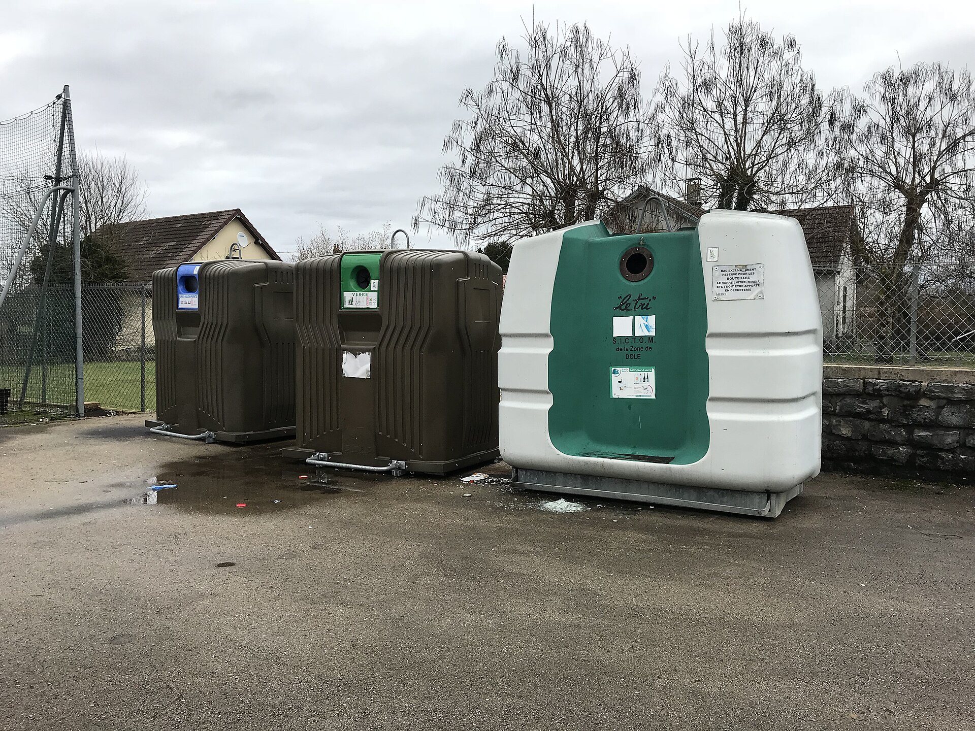 Rekke med containere for glass og papir langs en vei
