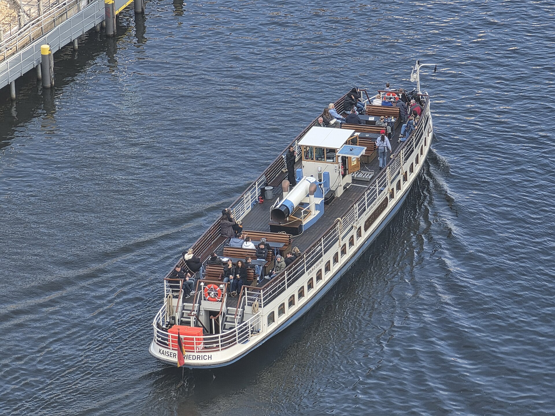 Hvit utfluktsbåt med passasjerer på vei nedover Spree
