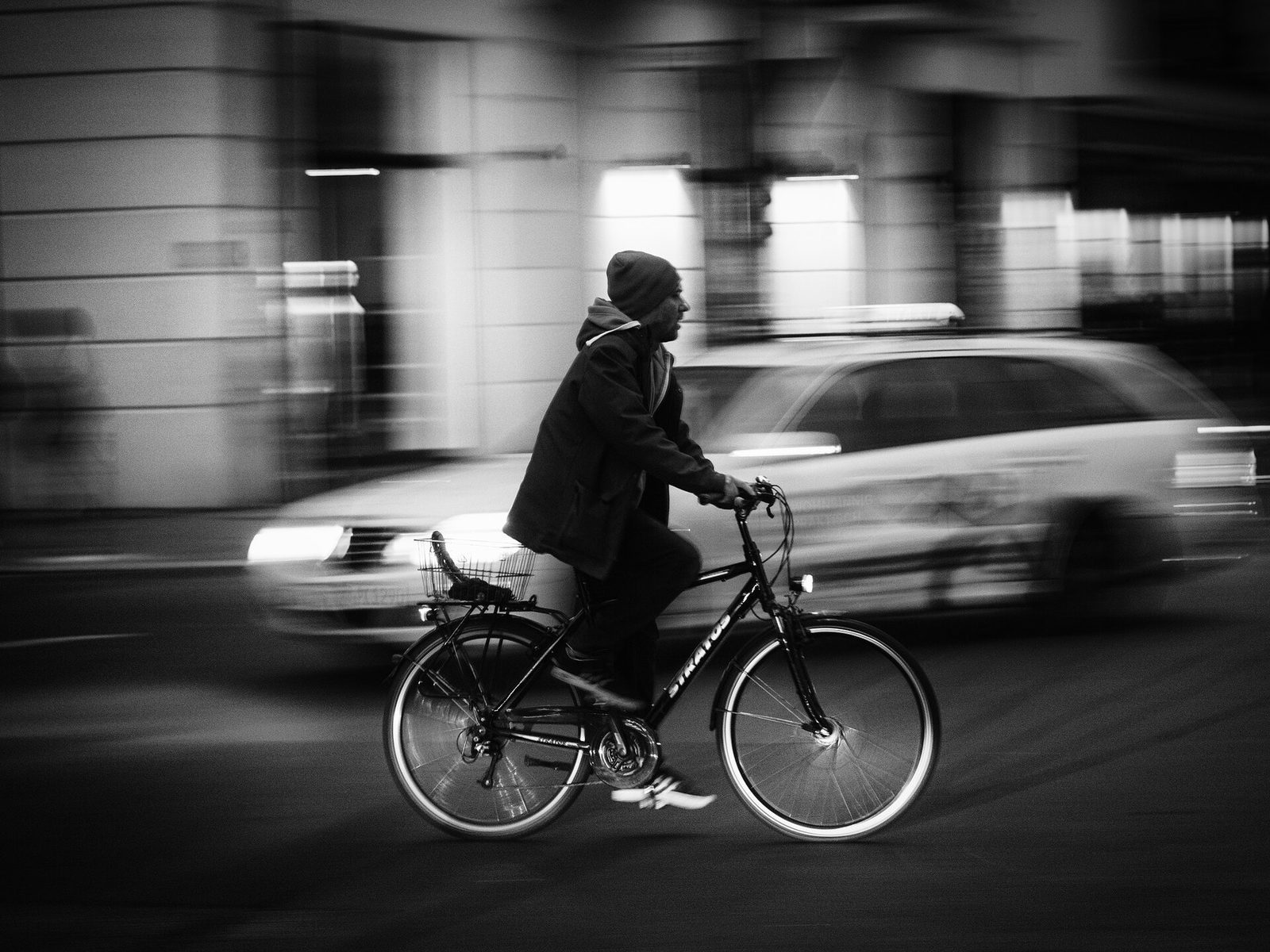 Syklist i bevegelse gjennom Berlin om kvelden, gjengitt i svart-hvitt