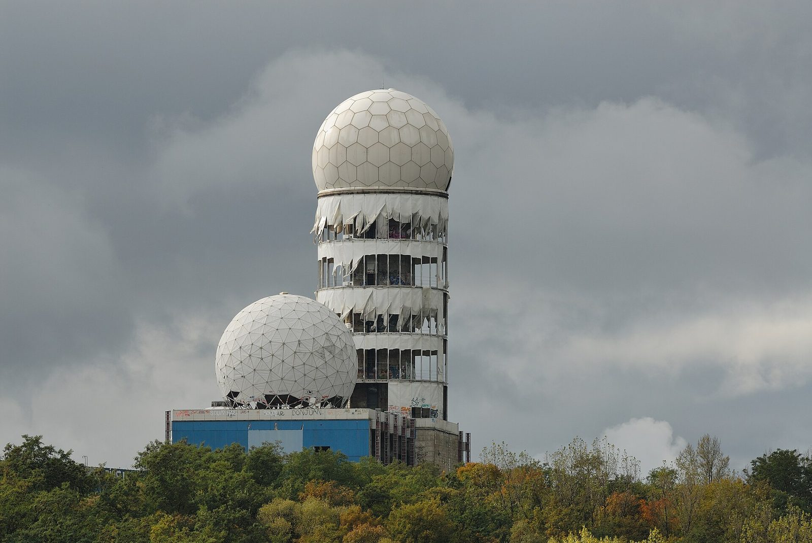 De to hvite radardomene på den forlatte avlyttingsstasjonen på Teufelsberg, ruvende over skogen mot en dramatisk skyhimmel