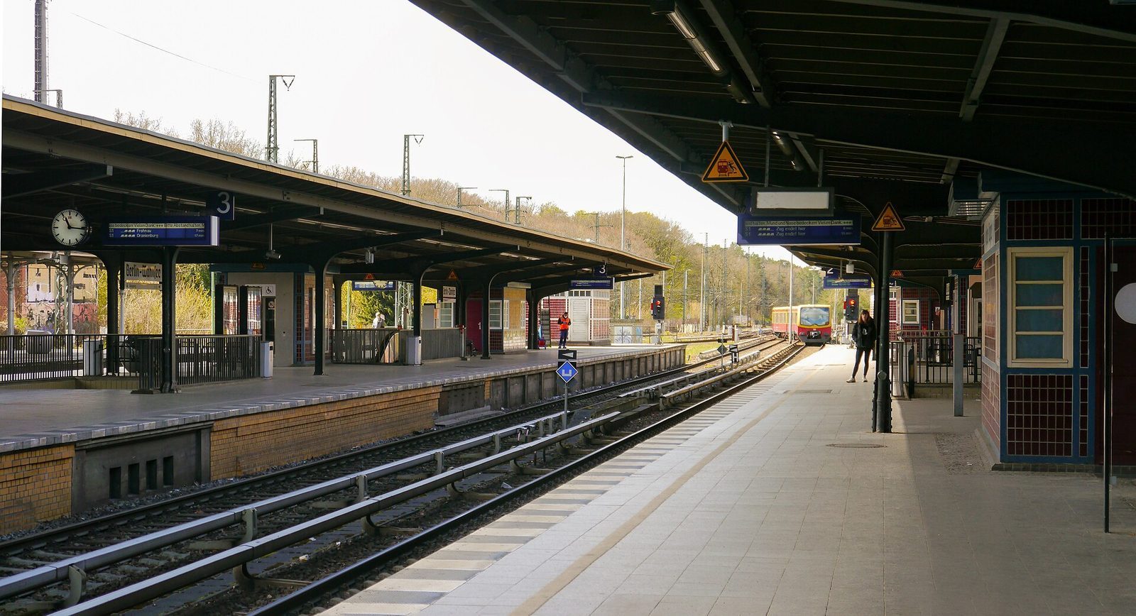 Perrongene pa Bahnhof Berlin-Wannsee med avgangstavler for S1 og et S-Bahn-tog pa vei inn