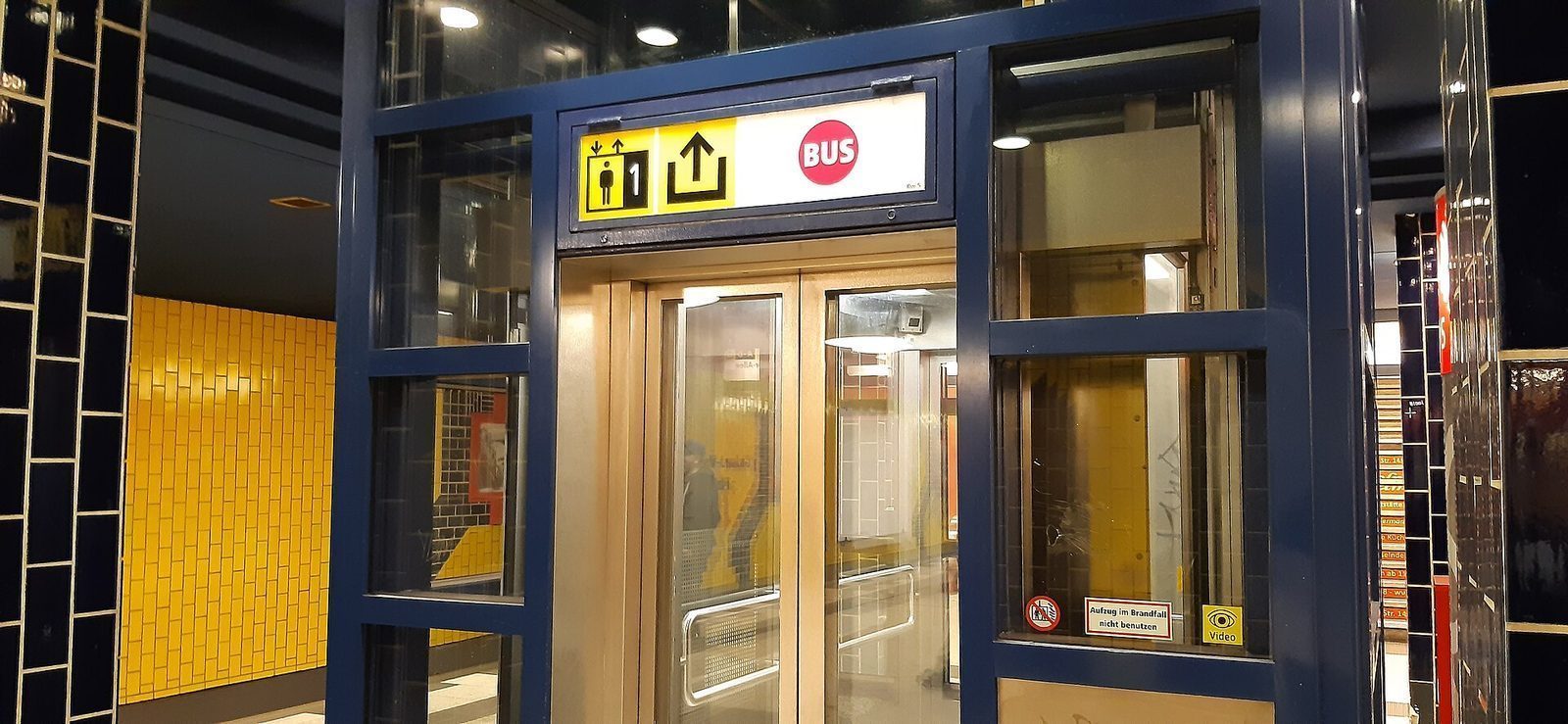 Glassheis med rullestolsymbol og etasjeskilt ned til perrongen på en Berlin-undergrunnsstasjon