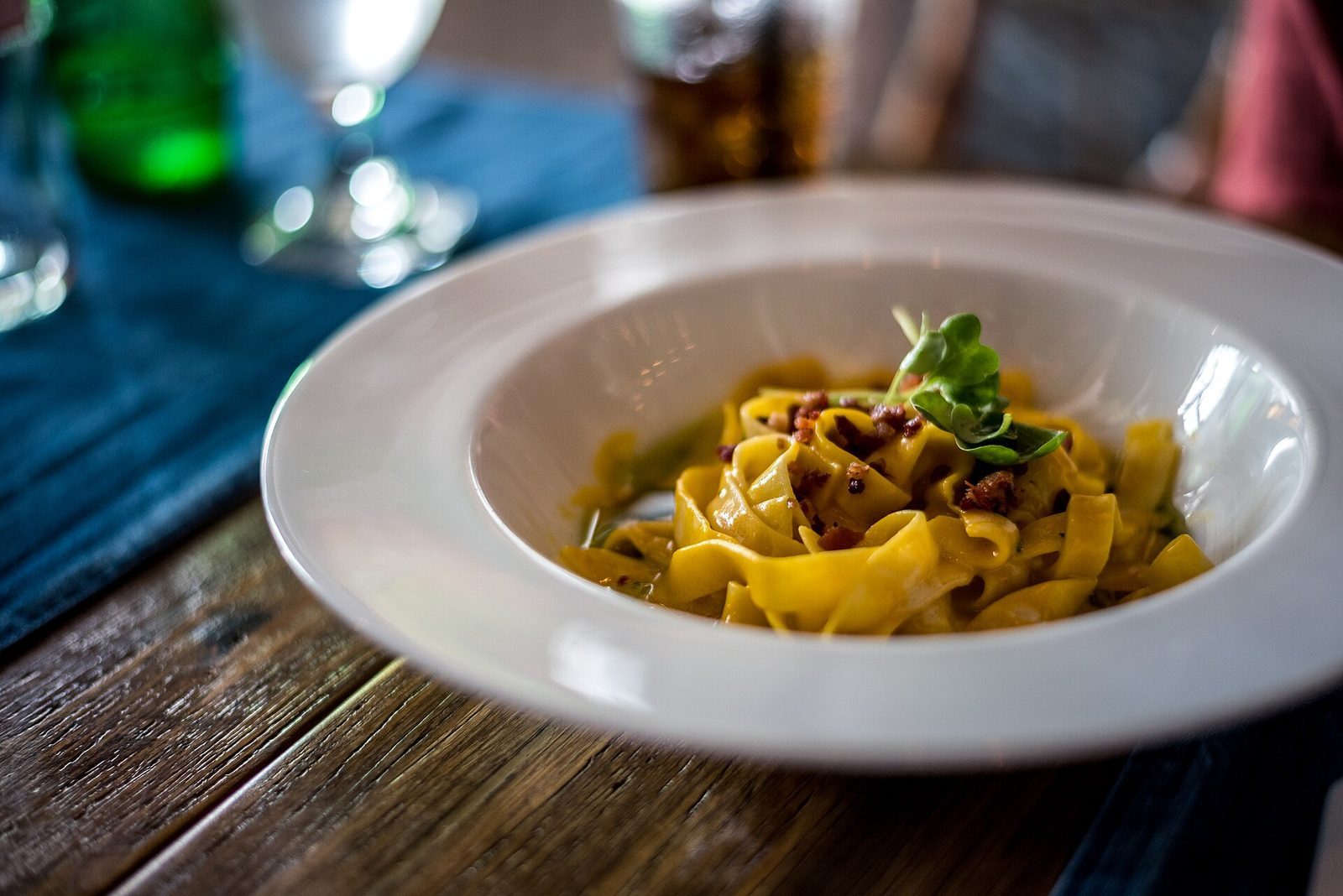 Tallerken med tagliatelle og pancetta pyntet med spirer i en restaurant