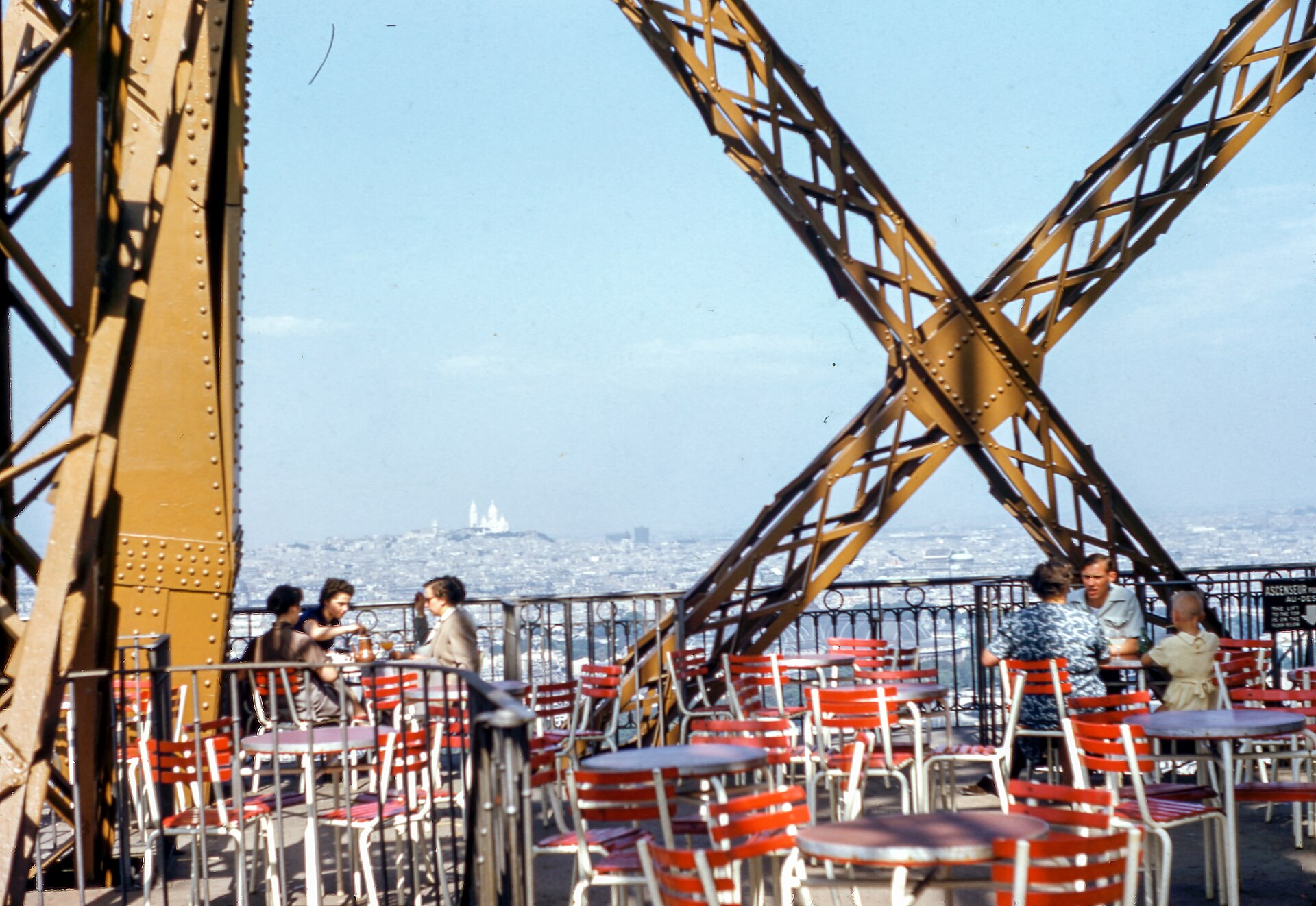 Gjester ved bord på en terrasse med utsikt over byen